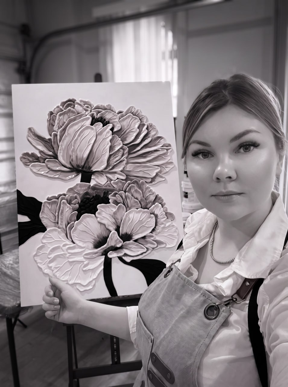 Irina Mastov in her studio, one hand on a peony painting on the easel
